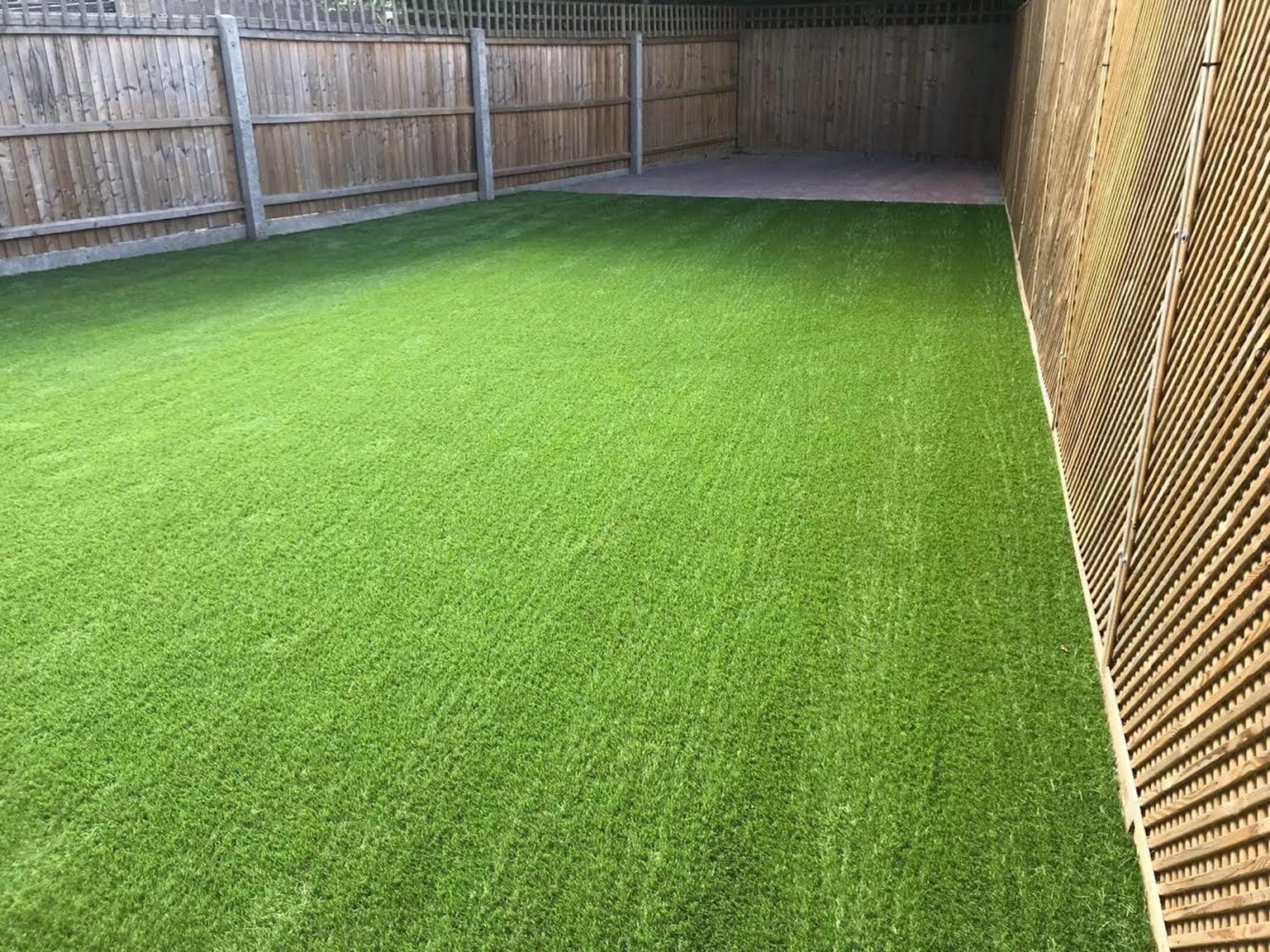 Artificial Grass newly installed up to fence line line.