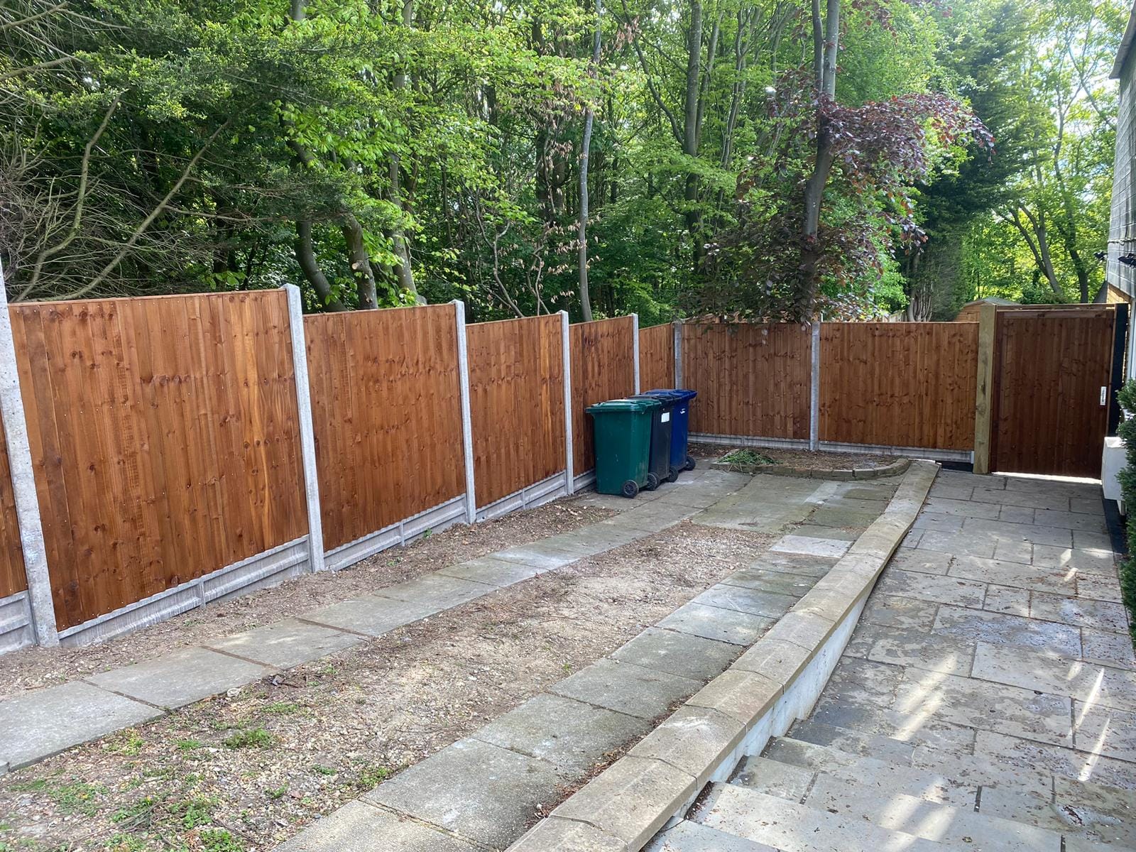 New closeboard fence panels with concrete gravel boards and posts on a sloped garden.