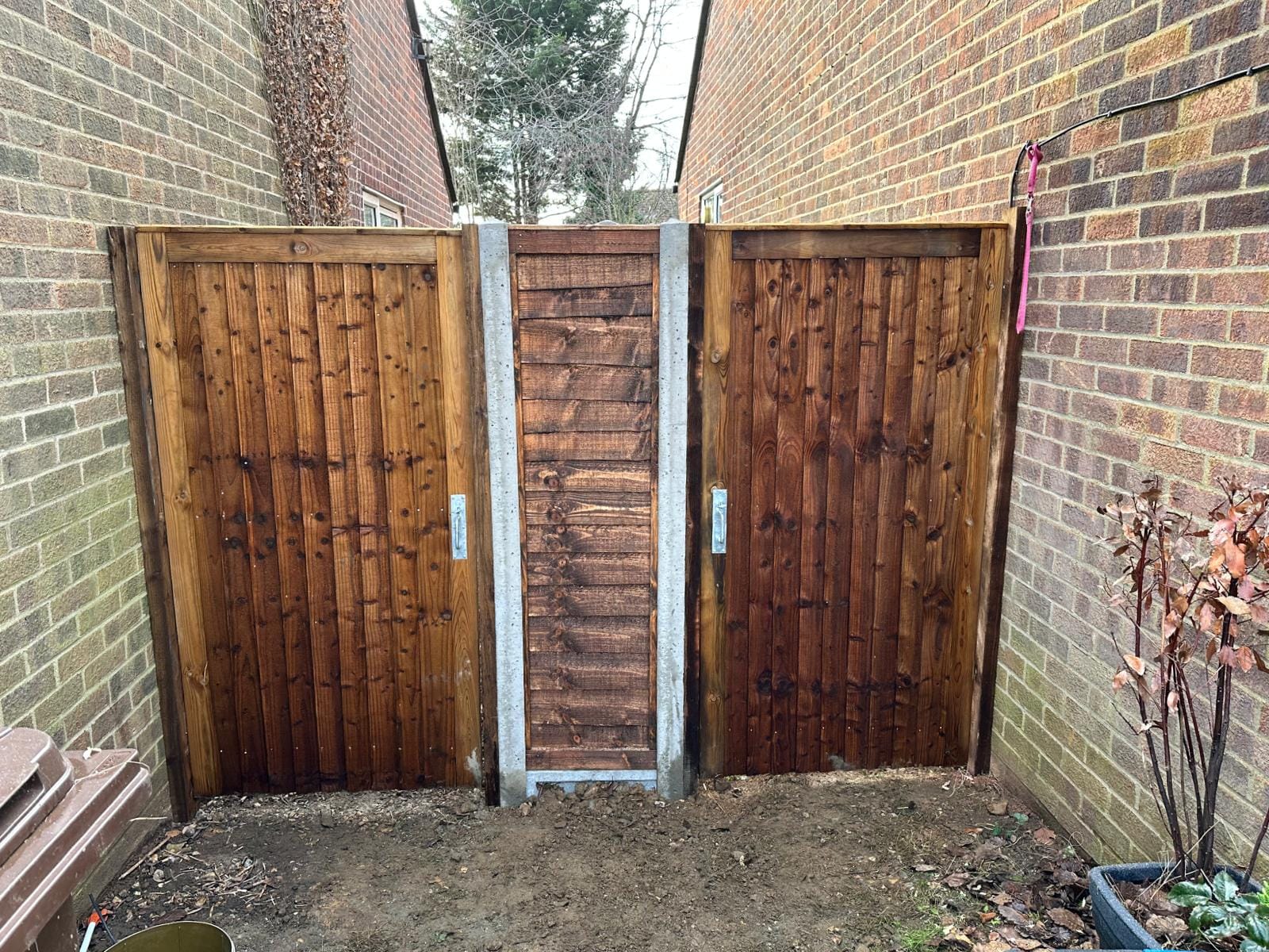 An image showing 2 gates installed side by side, approx 6ft high in dark brown.